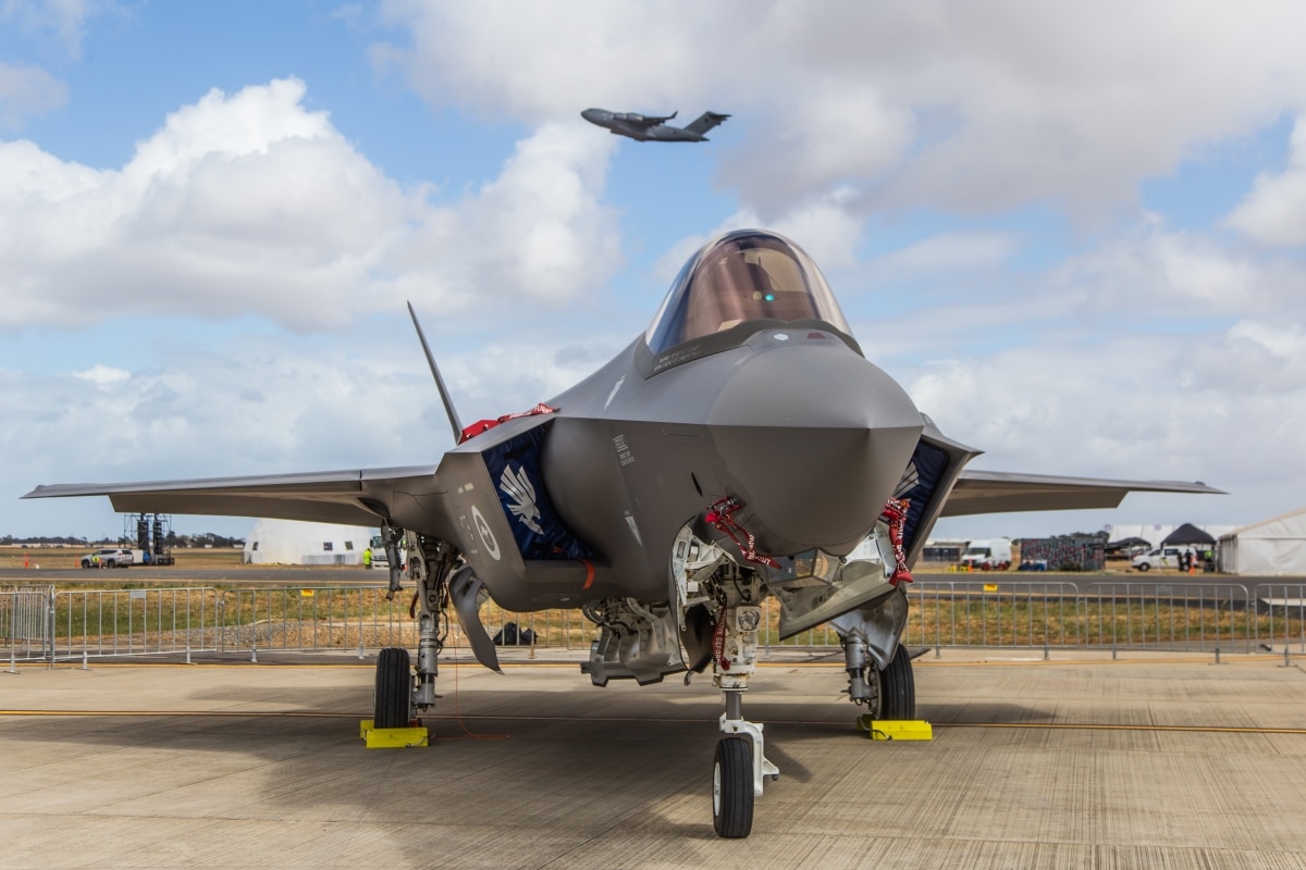 Adelaide, South Australia / Australia - Nov 08 2019: ADF RAAF F-35 Joint Strike Fighter (JSF) sits on the runway display for RAAF Edinburgh Airshow 2019 as a cargo plane departs in the background.