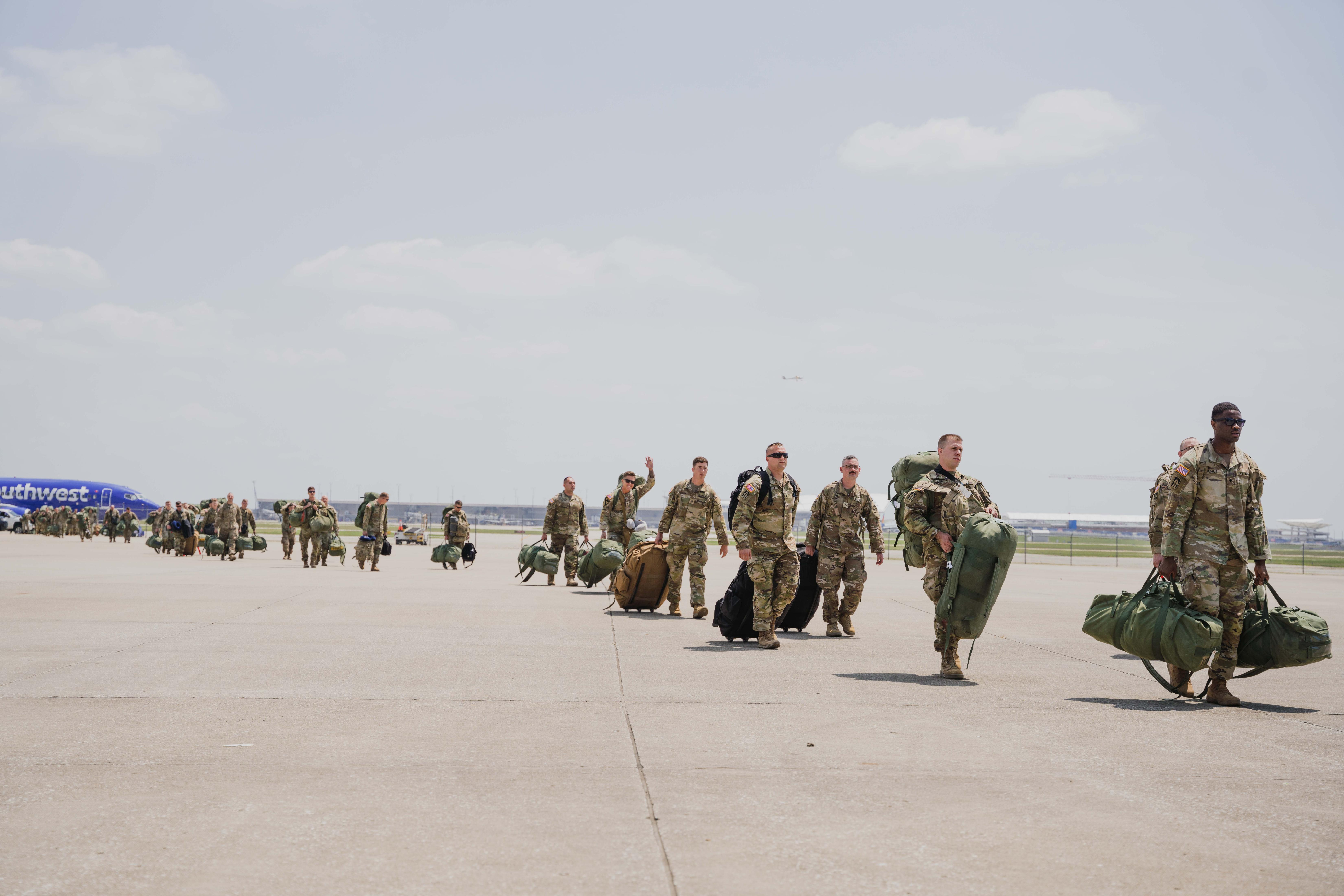 Indiana National Guard soldiers with the 1st Battalion, 163rd Field Artillery Regiment walk across a tarmac in Indianapolis, Aug. 3, 2023. Family members, friends and leaders gathered to greet the returning soldiers after a nine-month deployment in Iraq supporting Operation Inherent Resolve. (U.S. Army National Guard photo by Sgt. Hector Tinoco)